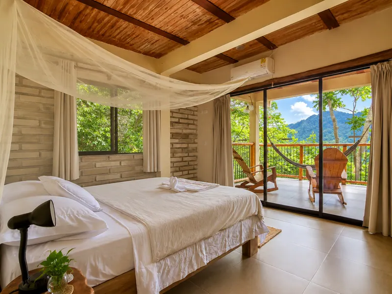 Bedroom with a large white bed and glass doors open to the terrace and mountains