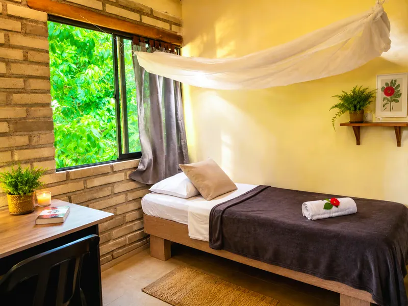 Bed under a large window with views of the trees